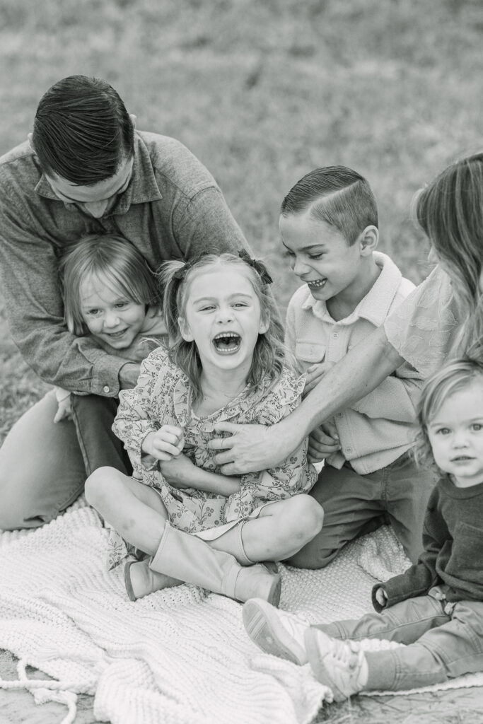 kids laughing during a full family tickle fight at a fall family outdoor session in east texas