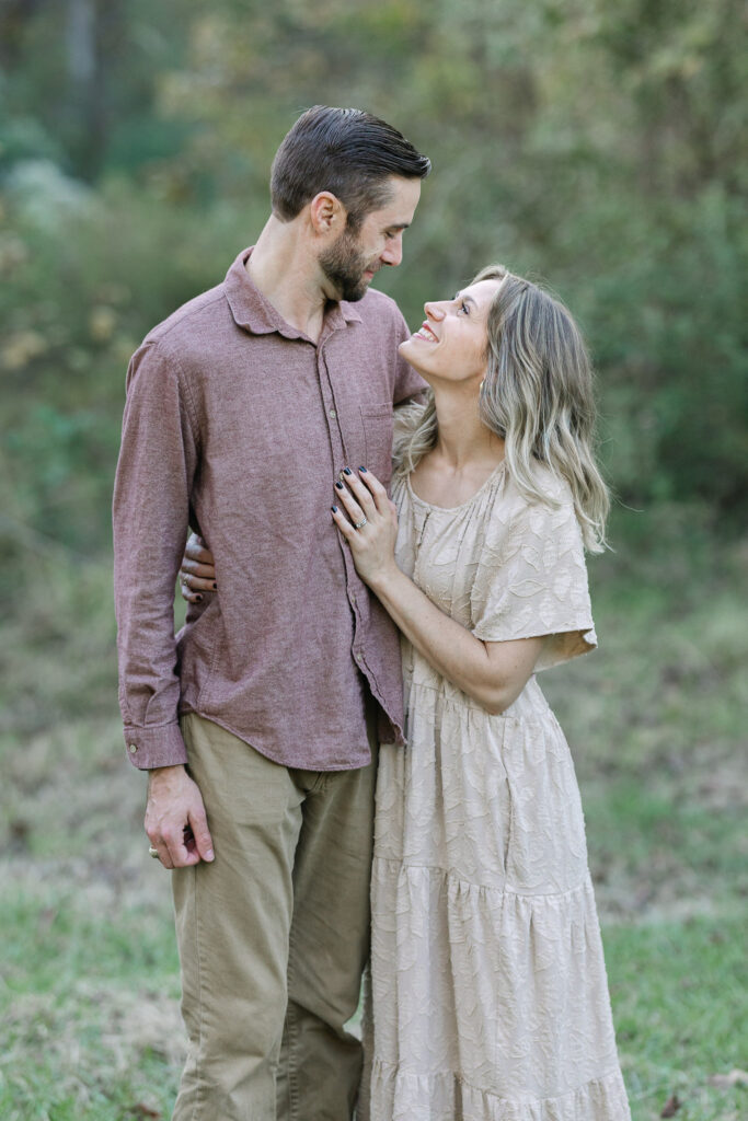 Mom and dad hugging in the golden sunset light in the tall trees during a family session in east texas
