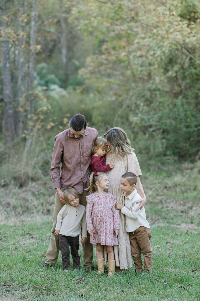 full family standing portrait against east texas trees during golden hour at a family session in east texas