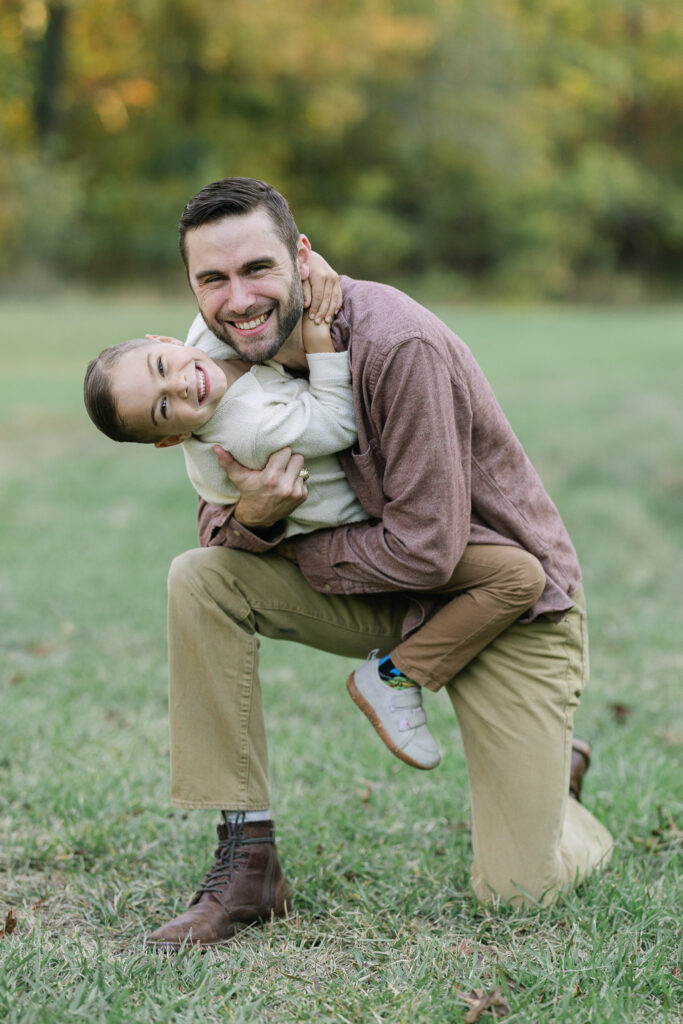 Dad crouching in an East Texas field while holding his son in a playful hug