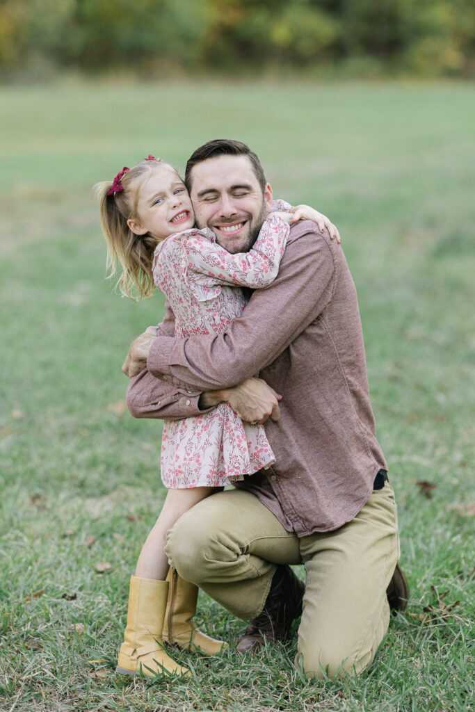 Daughter hugging her dad tightly during a playful fall photoshoot