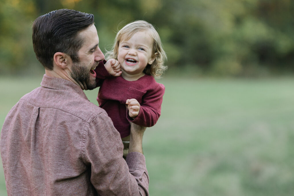 Dad playfully throwing his son in the air during fall family photos in east texas