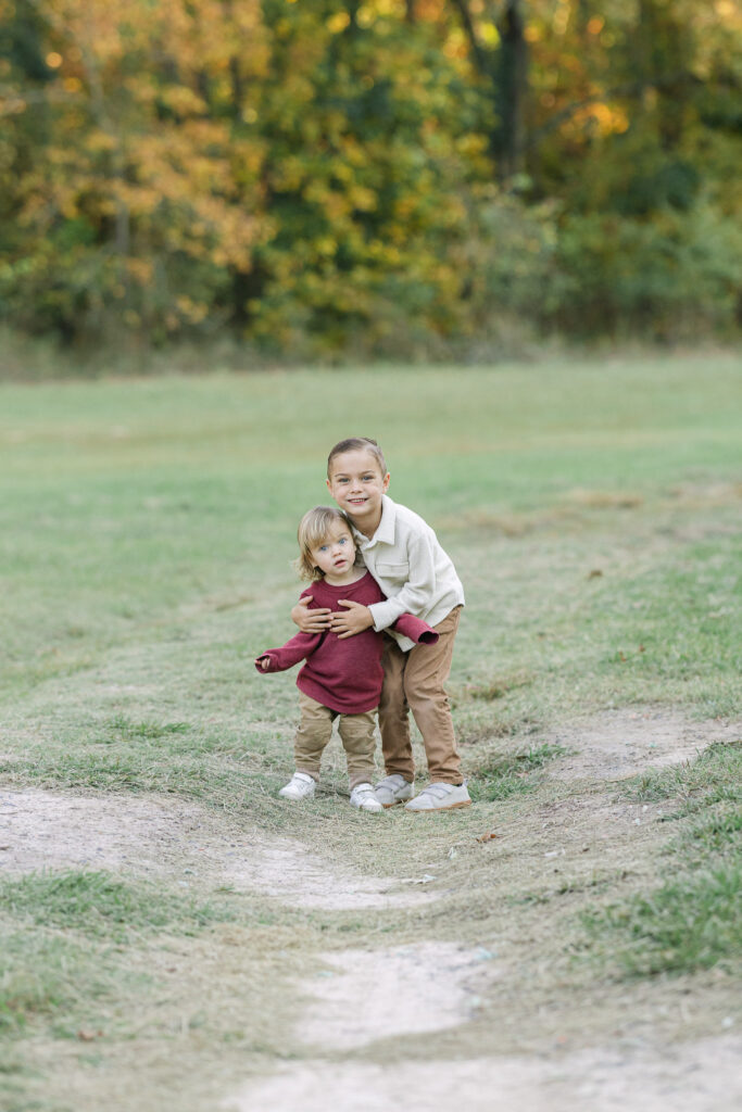 Two brothers hugging in an open field during their fall family photo session in east texas