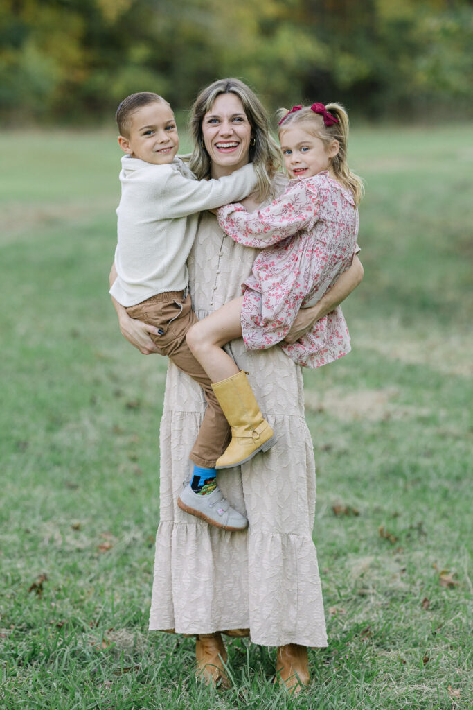 Mom smiling while holding two of her children during a fall family session
