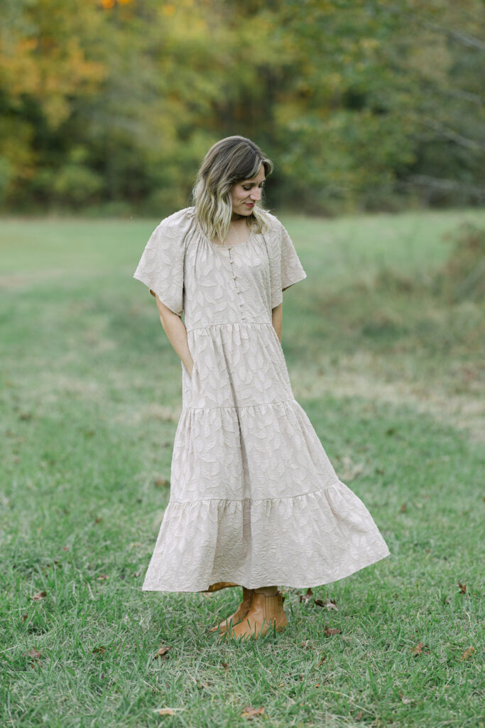 mom playfully swinging her dress side to side during a family fall session in east texas
